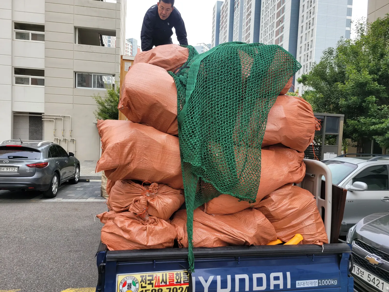 녹색 그물로 고정된 폐기물을 가득 실은 트럭